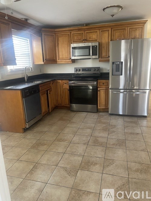 A kitchen with wooden cabinets and a stainless steel refrigerator.
