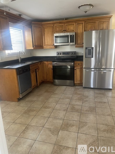 A kitchen with wooden cabinets and a stainless steel refrigerator.