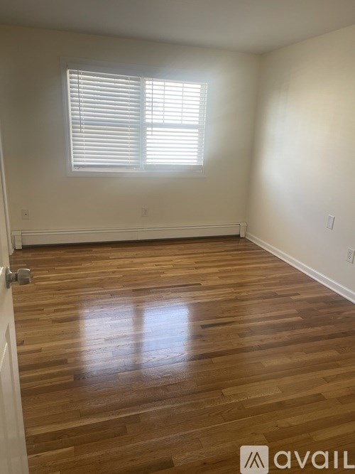 A room with wooden flooring and a window with blinds.