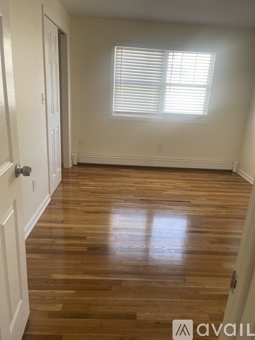 A room with wooden floors and a window with blinds.