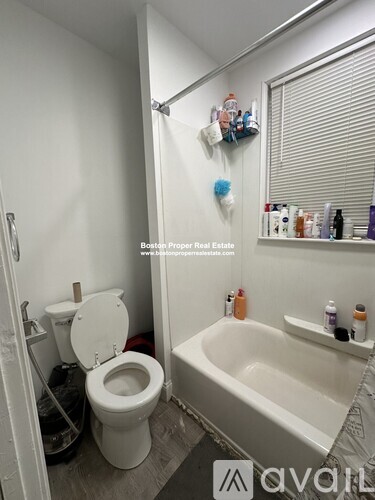 A white toilet is in a small bathroom with a white bathtub.
