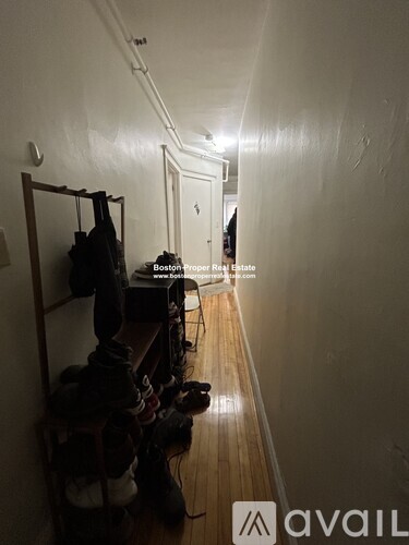 A hallway with a coat rack and shoes.