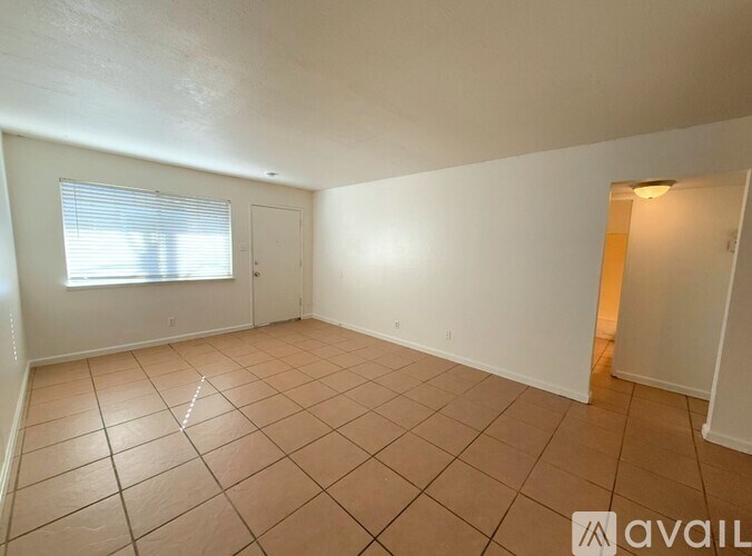 A room with tiled flooring and a window with blinds.