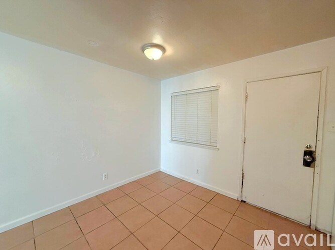 A room with a white door and a window with blinds.