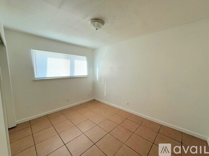 A room with a tiled floor and a window with blinds.