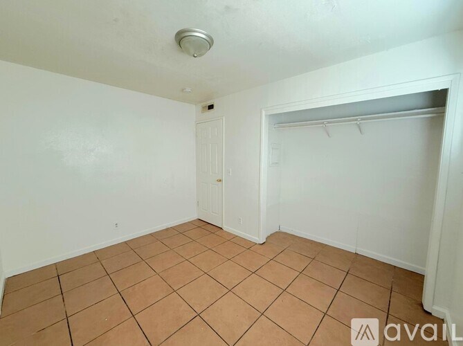 A room with a tiled floor and a closet with a shelf.