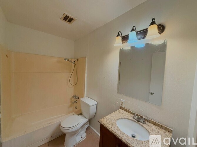 A bathroom with a toilet, sink, and mirror.