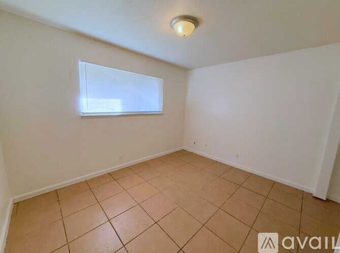 A room with a tiled floor and a window with blinds.