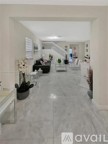 A spacious hallway with a marble floor and a staircase.