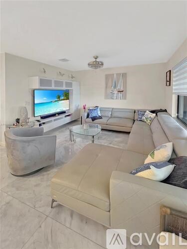 A living room with a large couch, a television, and a glass coffee table.