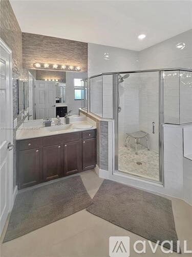 A bathroom with a walk-in shower and a vanity with a mirror above it.