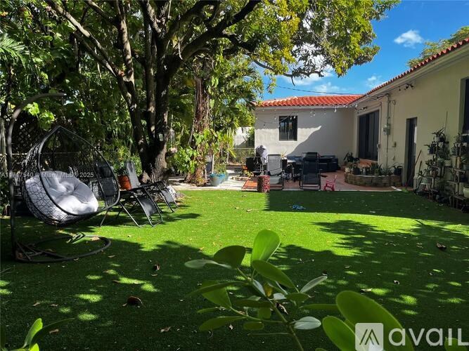A backyard with a lawn, trees, and a patio area.