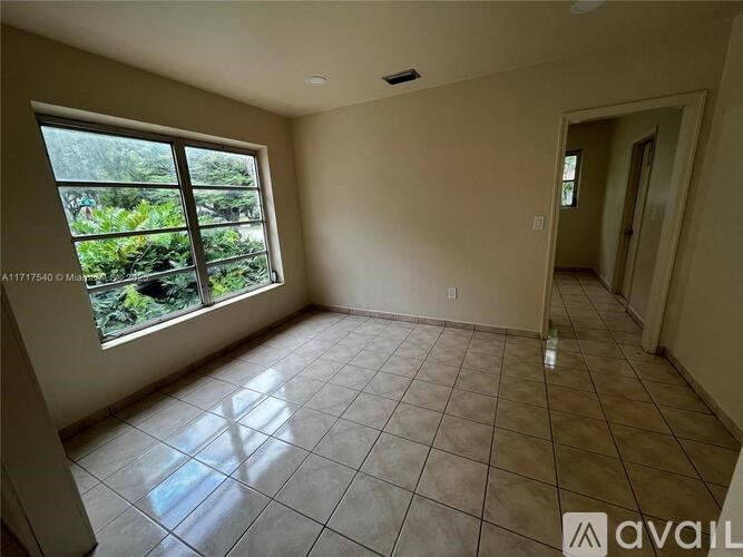 A room with tiled flooring and a large window overlooking a garden.