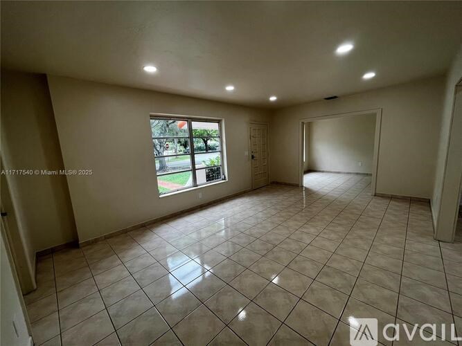 A spacious room with tiled flooring and a large window.