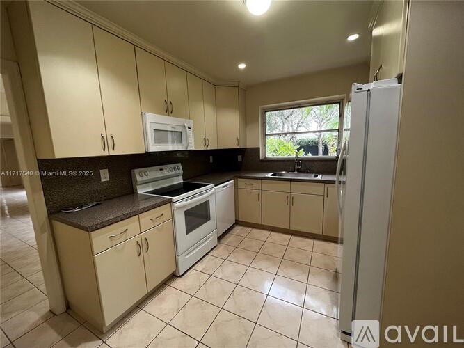 A kitchen with white appliances and beige cabinets.