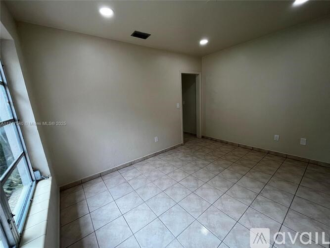 A spacious room with tiled flooring and a door leading to another room.