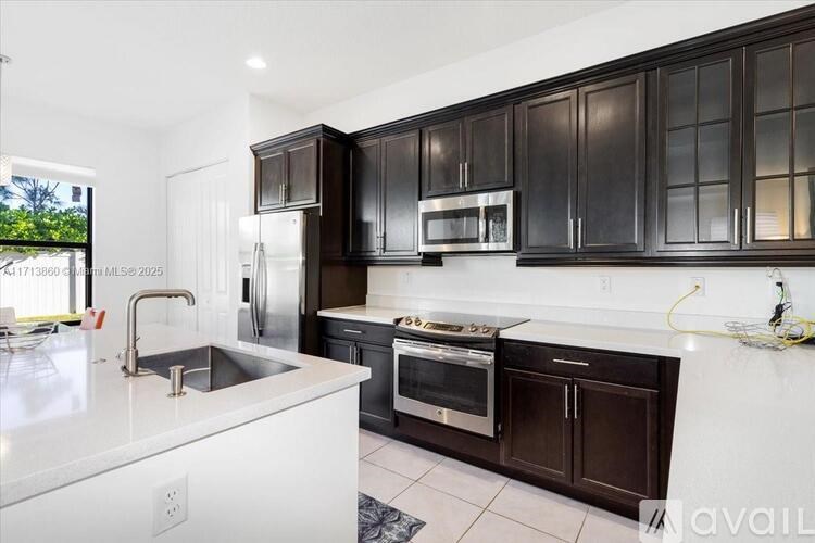 A modern kitchen with dark brown cabinets and stainless steel appliances.