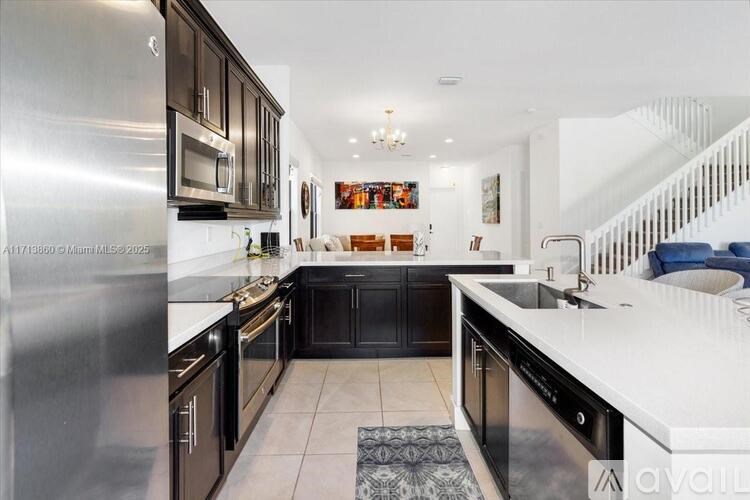 A modern kitchen with black cabinets and stainless steel appliances.