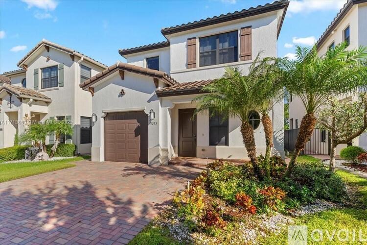 A large house with a driveway and a palm tree in front.