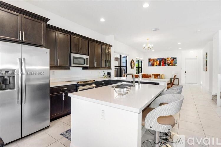 A modern kitchen with a white island and stainless steel appliances.