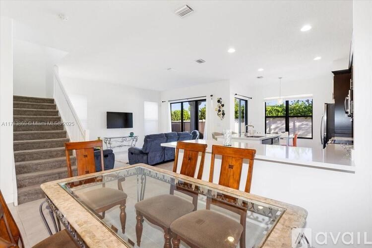 A modern living room with a glass table and a staircase.
