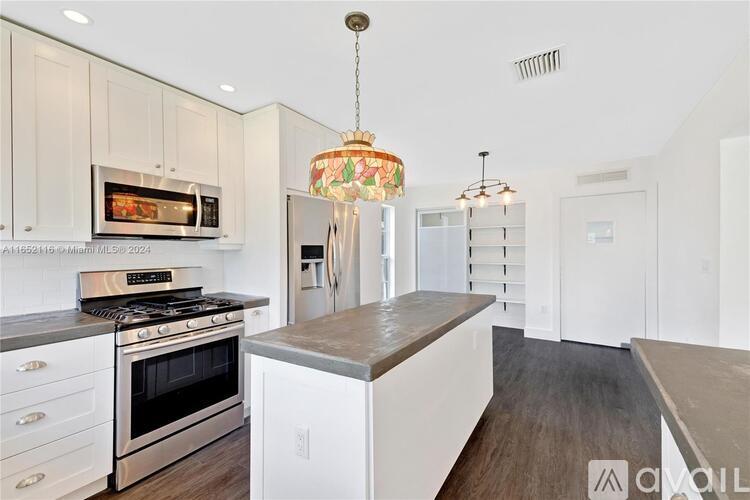A modern kitchen with white cabinets and a wooden island.