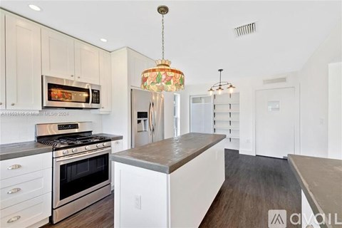 A modern kitchen with white cabinets and a wooden island.
