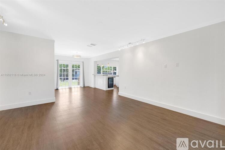 A spacious room with wooden flooring and white walls.