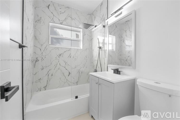 A bathroom with a marble wall and a white bathtub.
