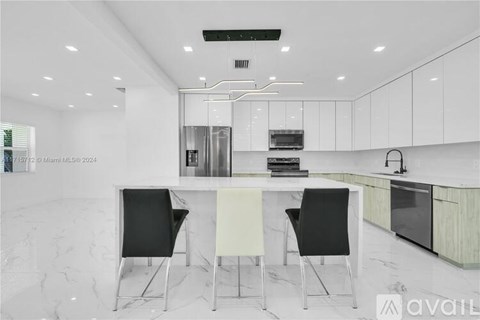 A modern kitchen with a white table and black chairs.