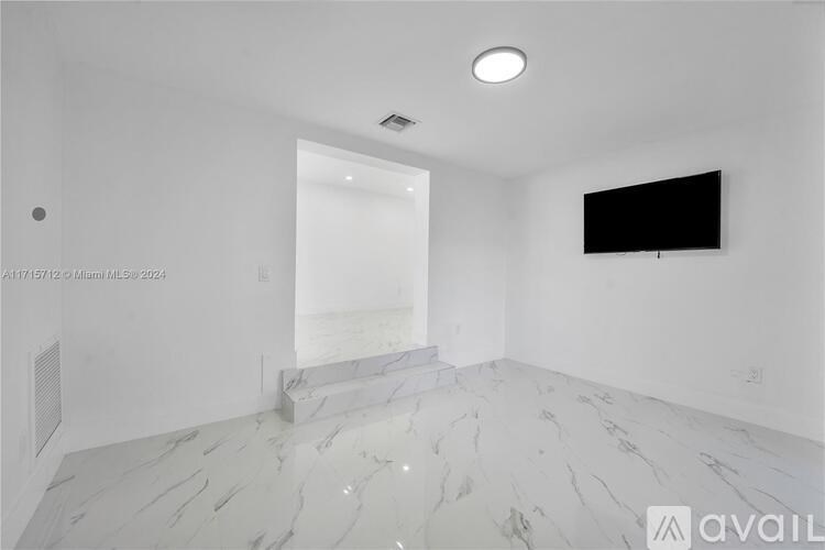 A room with a flat screen TV mounted on the wall and a marble floor.