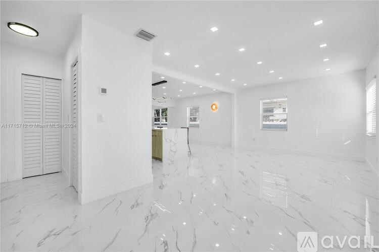 A spacious, white-walled room with marble flooring and a closed door on the left.