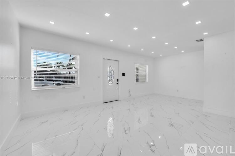 A spacious room with a marble floor and a large window with blinds.