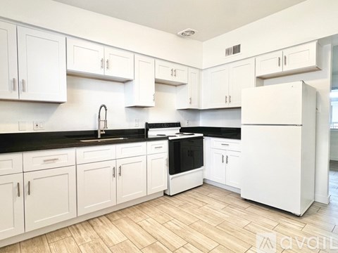 A kitchen with white cabinets and black countertops.