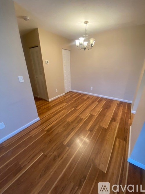 A room with wooden flooring and a chandelier.