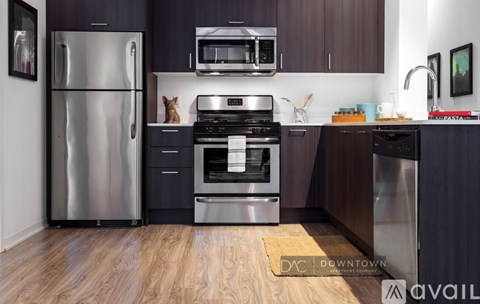A kitchen with a refrigerator, microwave, oven, and sink.