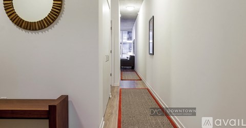 A hallway with a round mirror on the wall and a carpet on the floor.