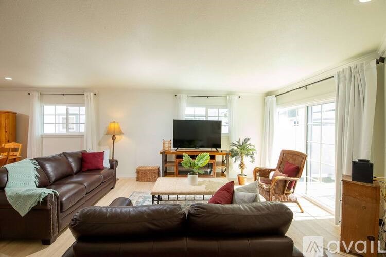 A living room with a brown leather couch and a wooden cabinet.