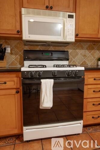 A white microwave oven is mounted above a stove in a kitchen.