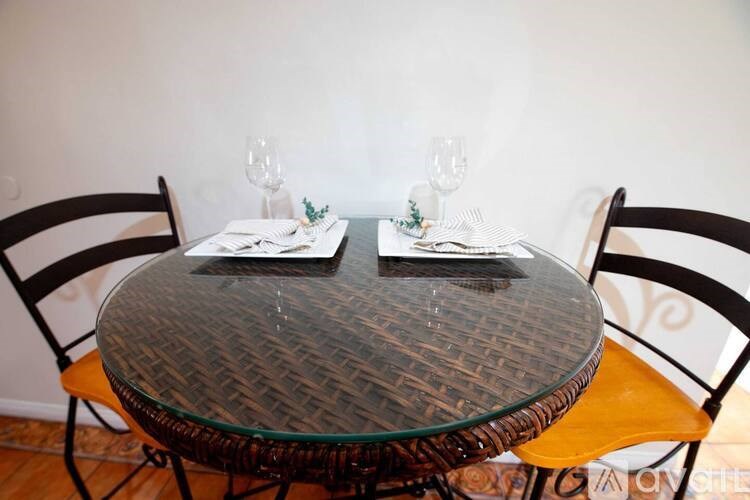 A glass table with two chairs and a place setting for two.