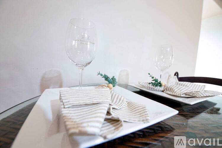A table set with white plates, striped napkins, and glasses.