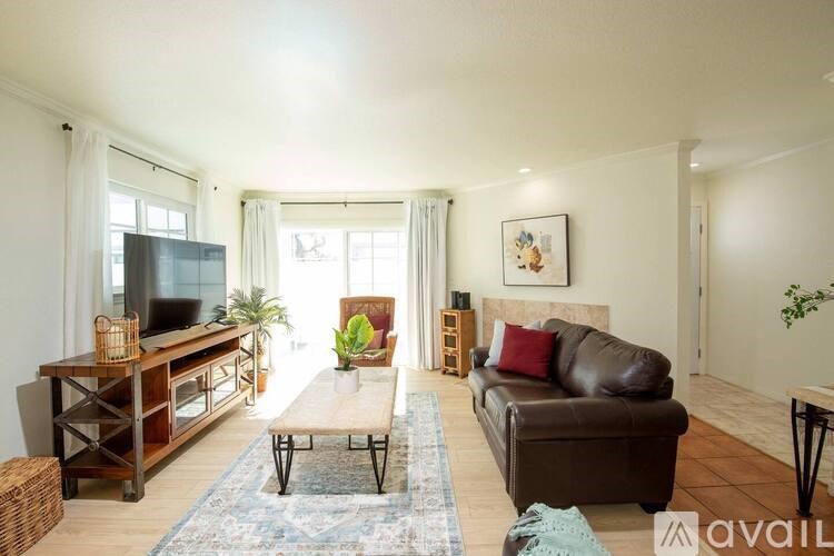 A living room with a brown leather couch, a wooden entertainment center, and a rug on the floor.