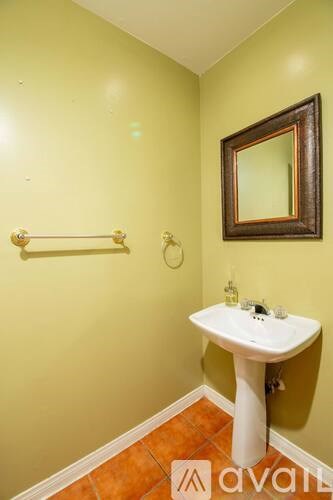 A bathroom with a white pedestal sink and a mirror above it.