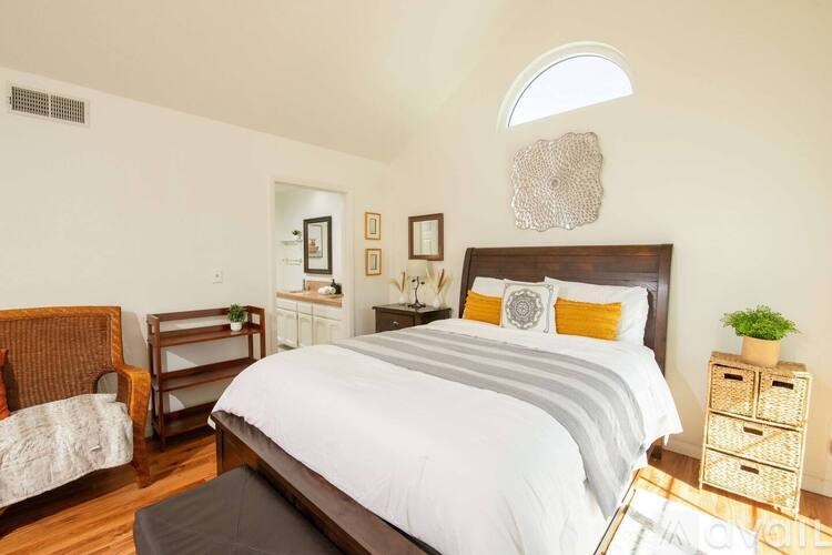 A bedroom with a large bed and a chair.