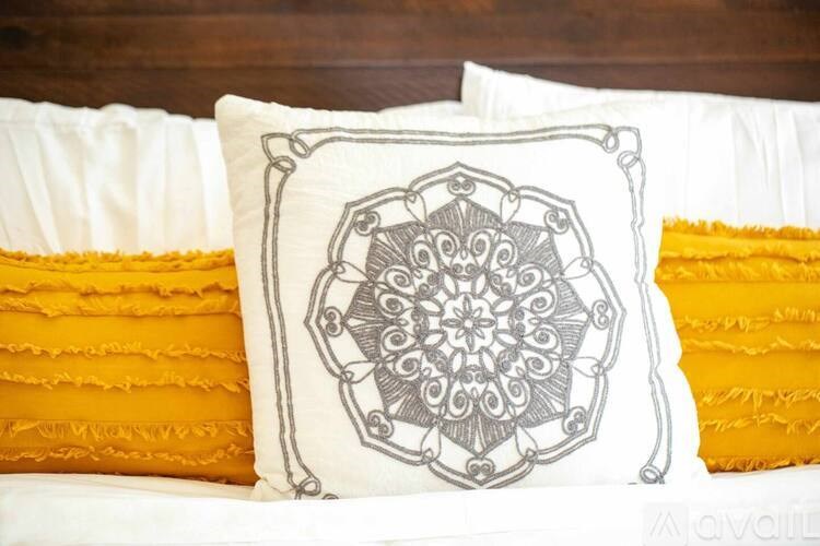 A bed with a white pillow with a mandala design on it.
