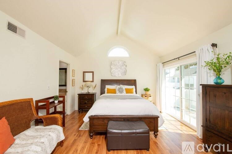 A bedroom with a large bed and a wooden dresser.
