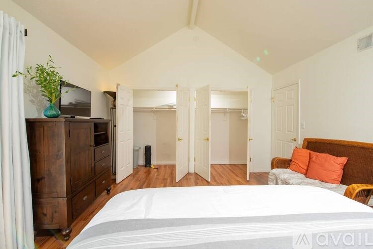 A bedroom with a large bed, a wooden dresser, and a television.