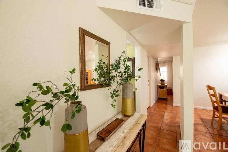 A hallway with a bench, a mirror, and a potted plant.