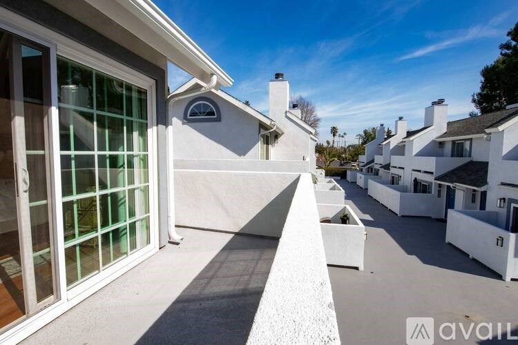A sunny day in a row of white houses with a clear blue sky.
