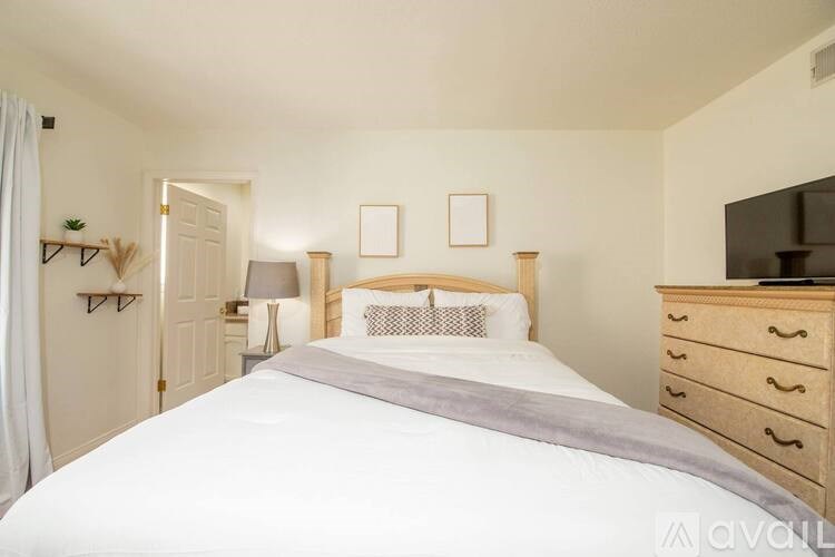 A bedroom with a large bed, a dresser, and a mirror.